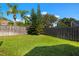 Fenced backyard featuring a well-maintained lawn, mature trees, and lush greenery offers privacy and space for outdoor activities at 19104 Cellini Pl, Lutz, FL 33558