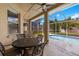 Covered patio with an iron table and chairs, with a view of the screened-in pool at 19104 Cellini Pl, Lutz, FL 33558