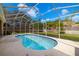 Tranquil screened-in pool area with surrounding greenery and blue sky above at 19104 Cellini Pl, Lutz, FL 33558