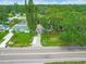 Aerial view of a single-story house surrounded by trees and located near a road at 2160 Ne Coachman Rd, Clearwater, FL 33765