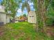 Backyard view of a white shed and a small wooden shed, with a grassy lawn and mature trees at 2160 Ne Coachman Rd, Clearwater, FL 33765