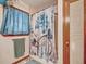 Charming bathroom with custom-designed shower curtain, towel rack, window, and an adjoining door to the hallway at 2160 Ne Coachman Rd, Clearwater, FL 33765