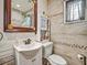 Bathroom featuring a sink, toilet, mirror and a patterned tile wall at 2160 Ne Coachman Rd, Clearwater, FL 33765