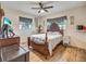 Bedroom with wood-look tile flooring, ceiling fan, and detailed wood furniture at 2160 Ne Coachman Rd, Clearwater, FL 33765