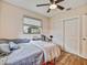 This bedroom features wood floors, a ceiling fan, a closet with sliding doors, and a window with plenty of natural light at 2160 Ne Coachman Rd, Clearwater, FL 33765