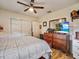 Bedroom with wood-look tile flooring, ceiling fan, and wood dresser with a TV at 2160 Ne Coachman Rd, Clearwater, FL 33765