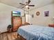 Bedroom featuring wood-look tile flooring, a ceiling fan and a dresser with TV at 2160 Ne Coachman Rd, Clearwater, FL 33765