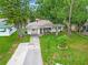 Charming single-story home with stone accents, mature trees, and a well-manicured front yard at 2160 Ne Coachman Rd, Clearwater, FL 33765