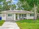 Charming single-story home with a well-maintained lawn, covered porch and an inviting outdoor seating area at 2160 Ne Coachman Rd, Clearwater, FL 33765