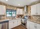 Bright kitchen featuring white cabinetry, granite countertops, stainless steel appliances, and tile backsplash at 2160 Ne Coachman Rd, Clearwater, FL 33765