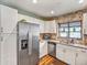 Well-lit kitchen with stainless steel appliances, granite countertops, white cabinets, and a large window at 2160 Ne Coachman Rd, Clearwater, FL 33765