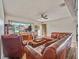 Comfortable living room featuring hardwood floors, leather sectional sofa, and a large TV with scenic views at 2160 Ne Coachman Rd, Clearwater, FL 33765