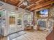 Inviting sun room with wood beam ceiling, fireplace, and French doors to an outdoor patio at 2160 Ne Coachman Rd, Clearwater, FL 33765