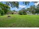 Over 1 acre backyard featuring a fire pit, playset, and lush landscaping, perfect for outdoor entertaining at 2306 S Valrico Rd, Valrico, FL 33596