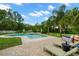 Backyard oasis with a large pool, lounge chairs, and lush landscaping, perfect for relaxation and recreation at 2306 S Valrico Rd, Valrico, FL 33596