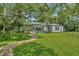 Spacious backyard featuring lush greenery, mature trees, a screened-in pool, and brick walkway leading to the home at 2435 Fox Forest Dr, Lutz, FL 33549