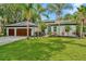 Beautiful single-story home boasting mature landscaping, palm trees, a charming blue entry door, and a two-car garage at 2435 Fox Forest Dr, Lutz, FL 33549