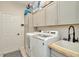 Bright laundry room with ample cabinet space, modern washer and dryer, and a utility sink at 2435 Fox Forest Dr, Lutz, FL 33549