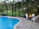 Enclosed pool area with a fire pit, lounge seating, and views of the manicured backyard for outdoor enjoyment at 2435 Fox Forest Dr, Lutz, FL 33549