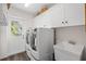 Bright laundry room featuring a washer, dryer, storage cabinets, and a utility sink with a view to the outside at 338 7Th N Ave, Tierra Verde, FL 33715