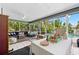 Bright sunroom with lounge furniture, a hanging chair, and a view of the inviting backyard pool at 338 7Th N Ave, Tierra Verde, FL 33715