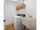 Functional laundry room with washer, dryer, utility sink, and storage baskets on shelving at 3408 W Swann Ave, Tampa, FL 33609