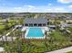 Aerial view of a community pool area showcasing lounge chairs, palm trees, and a modern clubhouse at 34797 Rainville Loop, Zephyrhills, FL 33541