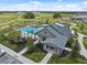 Aerial view of a community pool and clubhouse surrounded by manicured landscaping and palm trees at 34797 Rainville Loop, Zephyrhills, FL 33541
