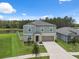 Exterior elevation featuring a two-story home with lawn and water views at 34797 Rainville Loop, Zephyrhills, FL 33541