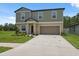 Attractive two-story home showcases a two-car garage and a verdant front yard adorned with lovely plants at 34797 Rainville Loop, Zephyrhills, FL 33541