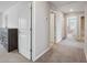 Hallway featuring gray carpet, an open doorway into the bathroom, and a dark brown dresser against the wall at 34797 Rainville Loop, Zephyrhills, FL 33541