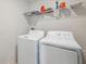 Bright laundry room featuring a white washer and dryer set and wire shelving at 34797 Rainville Loop, Zephyrhills, FL 33541