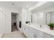 Bright bathroom featuring dual sinks, a large mirror, tile flooring, and a separate water closet at 34797 Rainville Loop, Zephyrhills, FL 33541