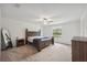 Spacious main bedroom features a ceiling fan, a large window, neutral carpet, and dark wood furniture at 34797 Rainville Loop, Zephyrhills, FL 33541