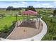 Community playground aerial view of unique play structure, green grass, and landscaping at 34797 Rainville Loop, Zephyrhills, FL 33541