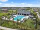 Resort-style pool and lounging area with tropical landscaping, umbrellas, and modern clubhouse in gated community at 34797 Rainville Loop, Zephyrhills, FL 33541