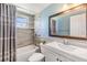 Charming bathroom with tiled walls, shower-tub combo and a framed mirror over the sink at 3818 Beechwood Dr, Holiday, FL 34691