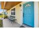 Inviting covered porch with seating area and a vibrant blue front door at 3818 Beechwood Dr, Holiday, FL 34691