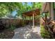 Paver patio with a wood pergola is surrounded by lush landscaping and a wooden fence at 409 E Frances Ave, Tampa, FL 33602