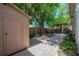 Backyard featuring a storage shed, a brick walkway, mature trees, and a covered patio area at 409 E Frances Ave, Tampa, FL 33602