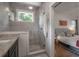 Modern bathroom featuring a glass shower, tiled walls, and a glimpse into a bedroom with wood floors at 409 E Frances Ave, Tampa, FL 33602