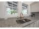 Bright kitchen sink beneath dual windows and a granite counter top at 409 E Frances Ave, Tampa, FL 33602