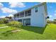 Beautiful two-story home with a screened balcony, outdoor seating, and a lush green lawn and blue paint at 4123 Daisy Dr, Hernando Beach, FL 34607