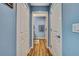 Hallway leads to a bathroom featuring wood floors, blue walls, and white doors at 4123 Daisy Dr, Hernando Beach, FL 34607