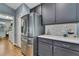 Close-up of a stainless steel refrigerator surrounded by modern gray cabinets and a white subway tile backsplash at 4123 Daisy Dr, Hernando Beach, FL 34607