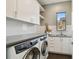 Modern laundry room with white cabinetry, sink, and front-load washer and dryer at 443 Lucerne Ave, Tampa, FL 33606