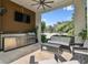 Relaxing covered patio with outdoor kitchen including stainless grill and countertop space, plus comfortable seating area at 443 Lucerne Ave, Tampa, FL 33606