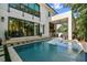 Backyard pool with modern design, covered patio, outdoor seating, and lush landscaping. Enjoy outdoor living at its finest at 443 Lucerne Ave, Tampa, FL 33606