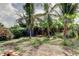 Fenced backyard featuring green grass, garden with lush plants, and fruit trees at 4479 Newark N St, St Petersburg, FL 33714