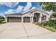 Beautifully landscaped home exterior featuring a large driveway and a 3-car garage at 5141 Riva Ridge Dr, Wesley Chapel, FL 33544